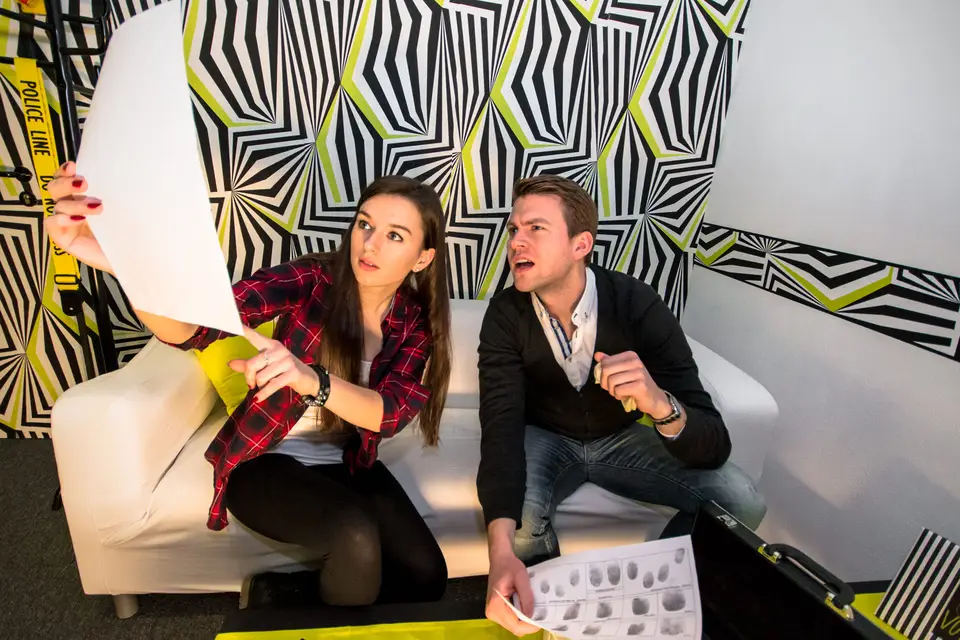 Two players on a white sofa examining clues in Out of Control